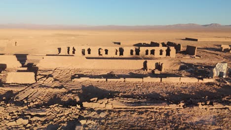 Drone image of abandoned ruined adobe facades, image descending to pass over the walls
