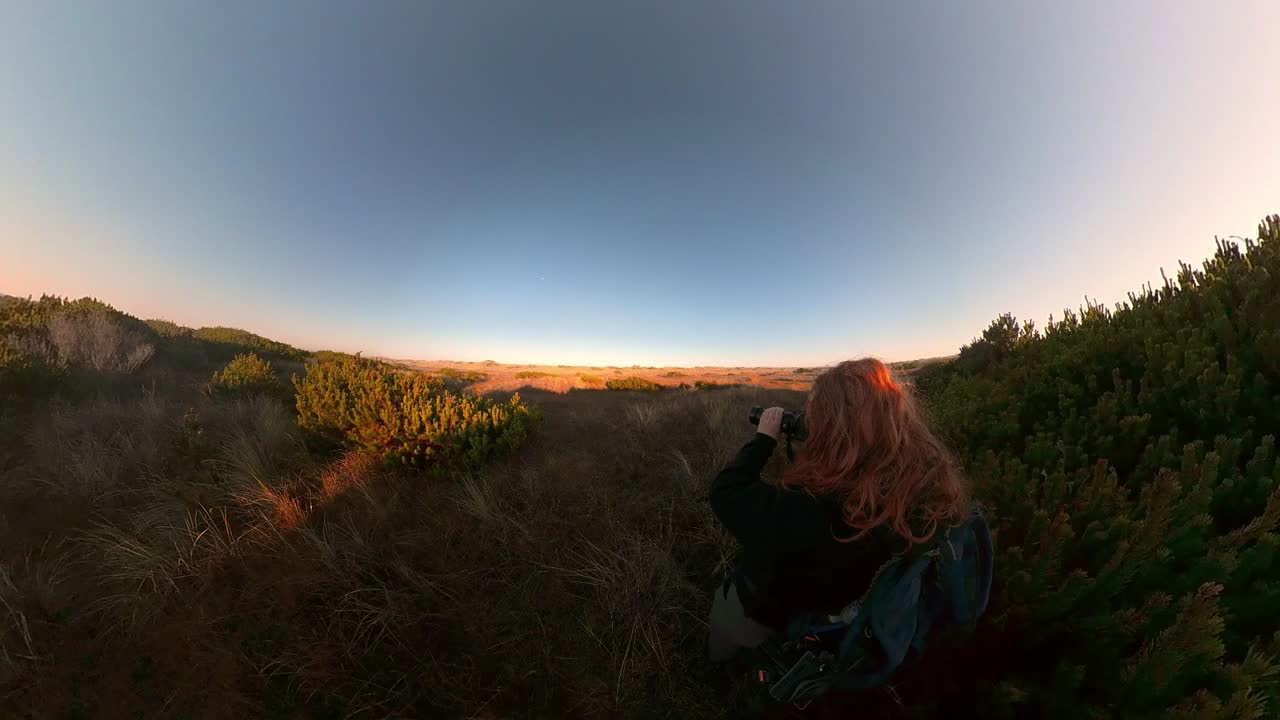 Kızıl saçlı bir adam Bandon Plajı'nda ötücü kuşların fotoğraflarını çekiyor.