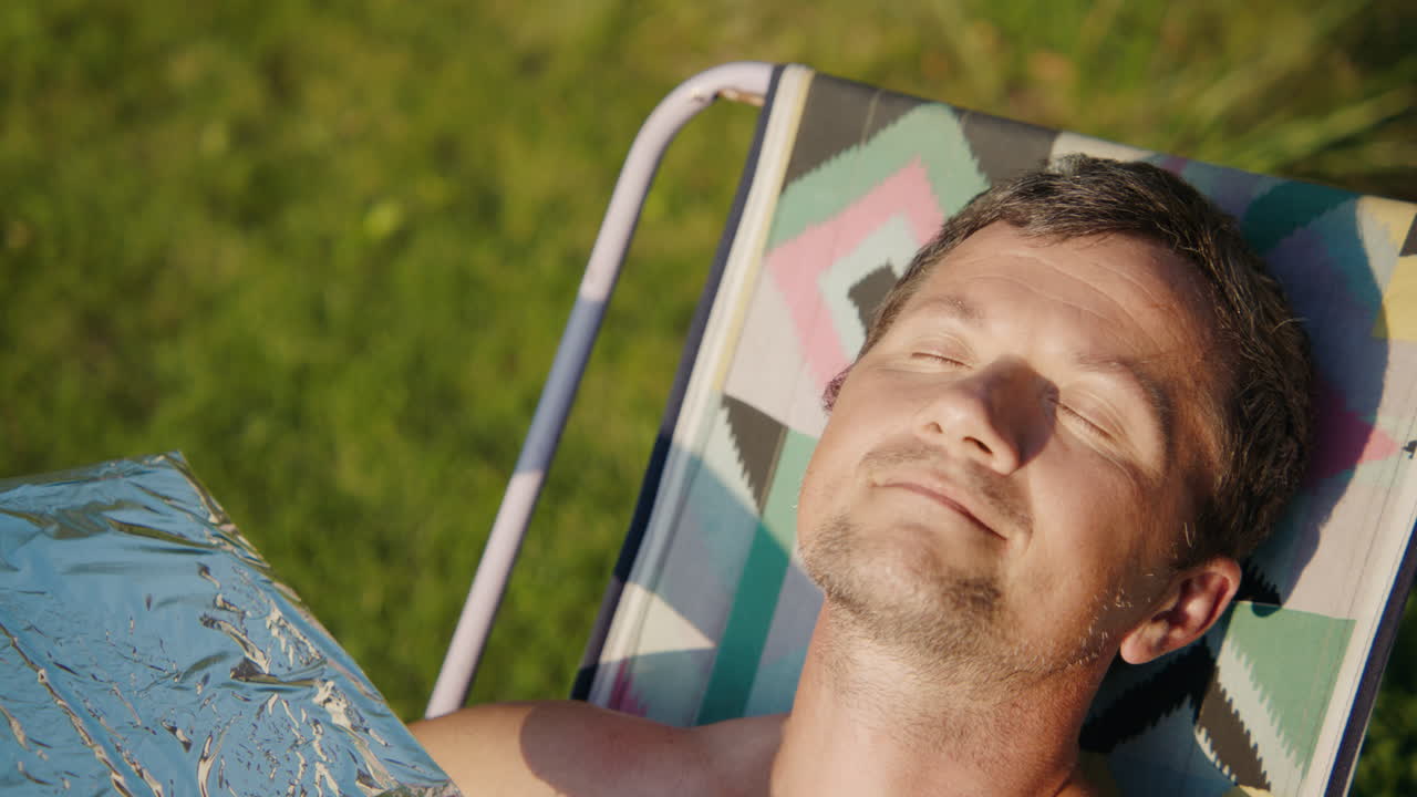 Uomo che prende il sole su una sedia da giardino