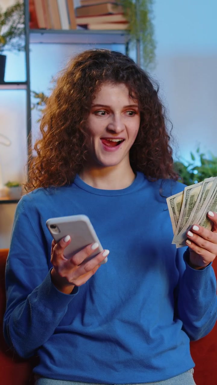 Mujer rica exitosa sosteniendo un teléfono inteligente y agitando billetes de dólares aficionado al dinero calculando el presupuesto del hogar