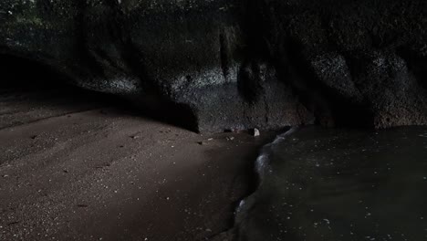 water recedes from sandy beach between rocks