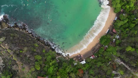 Über-Dem-Blau-Sehen-Sie-Aus-Der-Drohnenperspektive-Den-Kristallklaren-Strand-Von-Carrizalillo-Und-Das-Surfen-In-Puerto-Escondido,-Oaxaca,-Mexiko