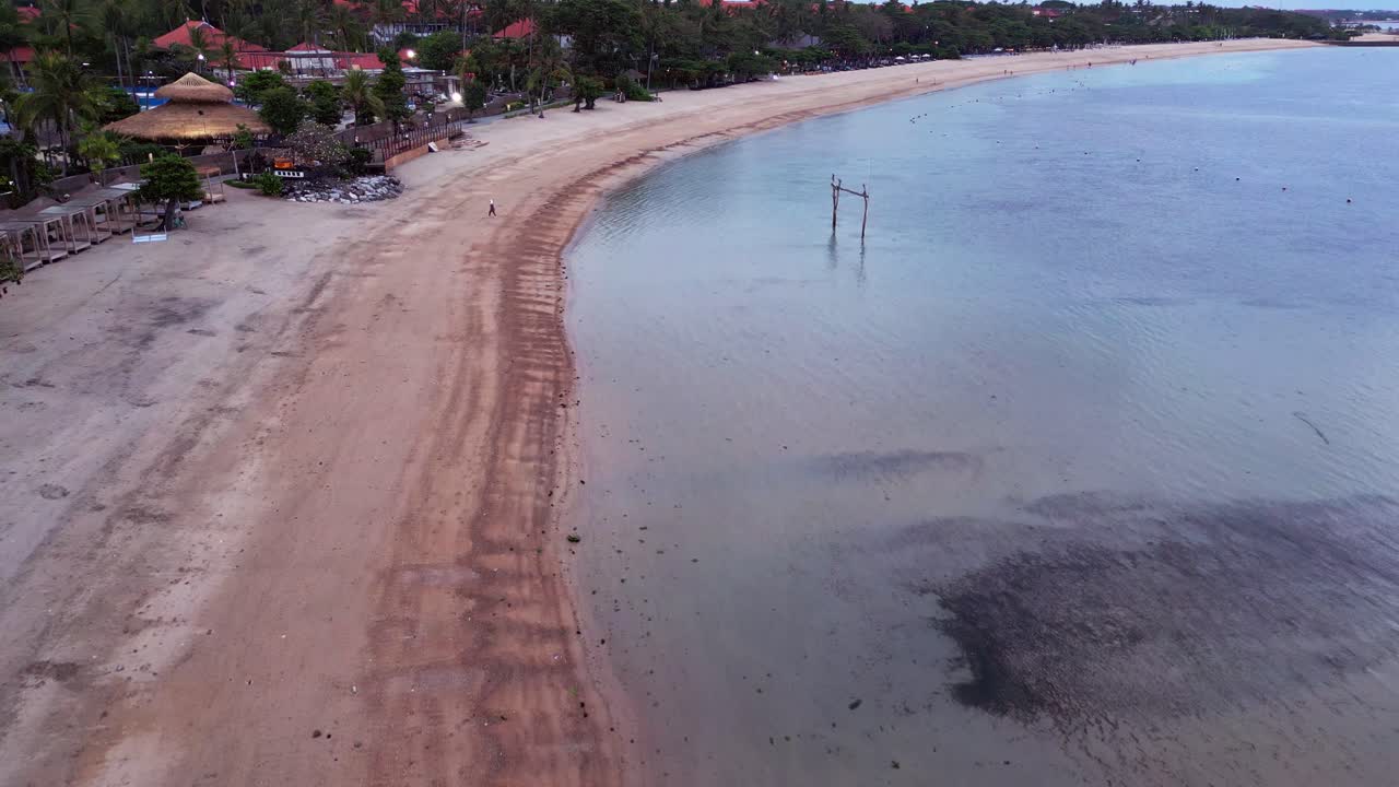 Tranquillo volo di drone su una spiaggia serale deserta con onde leggere, costa uniforme e luce tropicale soffusa, che mette in risalto la bellezza della natura incontaminata lungo le pacifiche coste dell'Indonesia