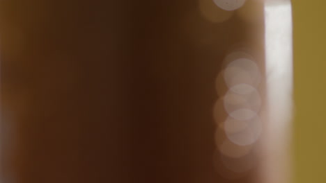 Close-Up-Of-Condensation-Droplets-On-Revolving-Takeaway-Cans-Of-Cold-Beer-Or-Soft-Drinks-Against-Yellow-Background