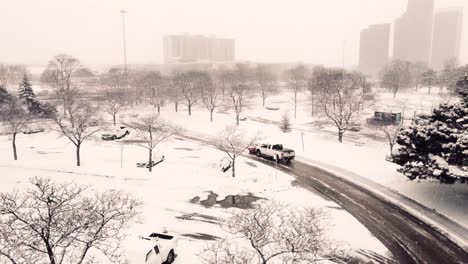 Aerial-view-truck-plowing-snow-with-snowplough-in-heavy-winter-storm