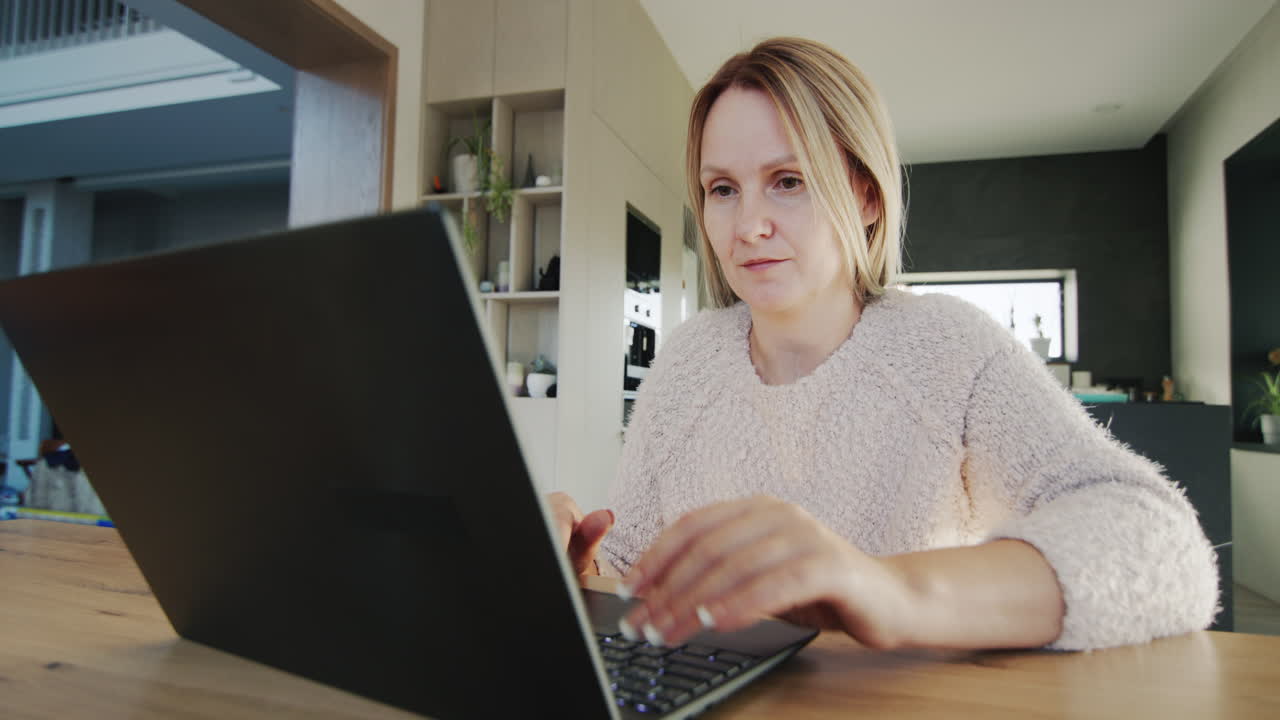 Middle-aged woman works at home, uses a laptop. Remote work from home