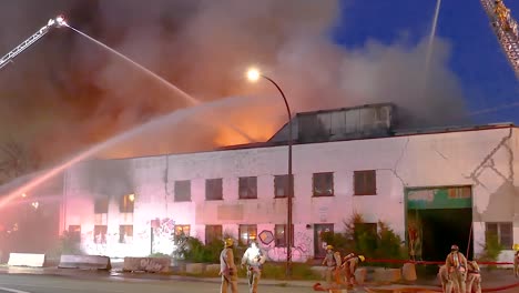 massive fire engulfs building at night; firefighters battle blaze