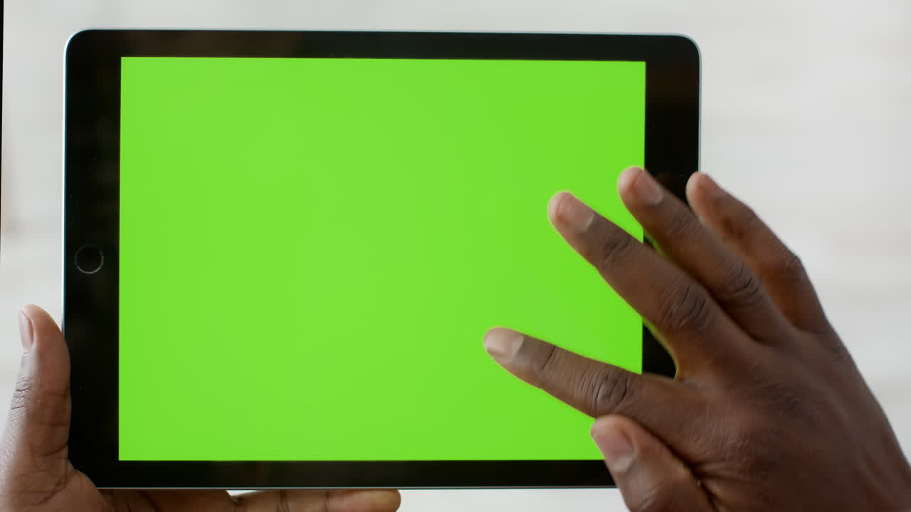 Person using a tablet with a green screen