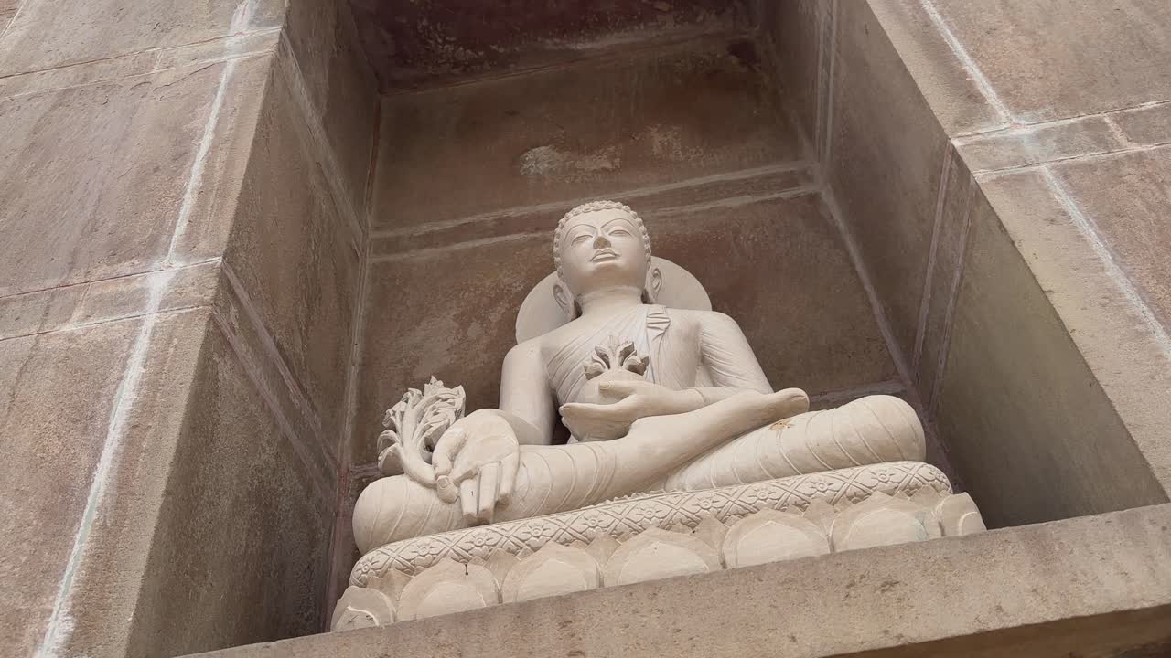 camera circling around a stone statue of buddha at sarnath temple, commemorating Buddha's first sermon