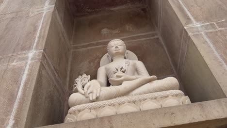camera circling around a stone statue of buddha at sarnath temple, commemorating buddha's first sermon