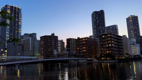 horizonte de la ciudad y el puente que se refleja en un río al crepúsculo
