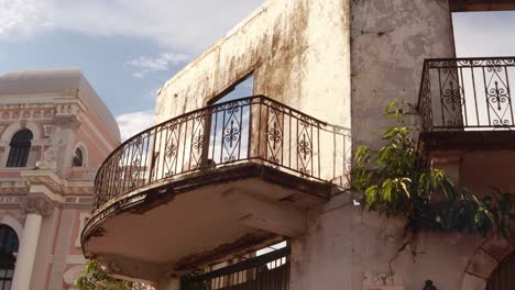 balcón de una antigua estructura de edificio abandonada con el interior demolido y la pintura descascarada de las paredes, vegetación que crece desde la fachada de una construcción histórica en panamá casco viejo durante el día