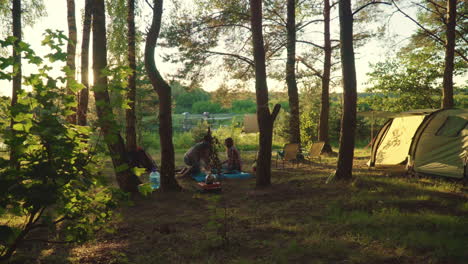 travelers drink tea near their tent in rays of evening sun. group of tourists