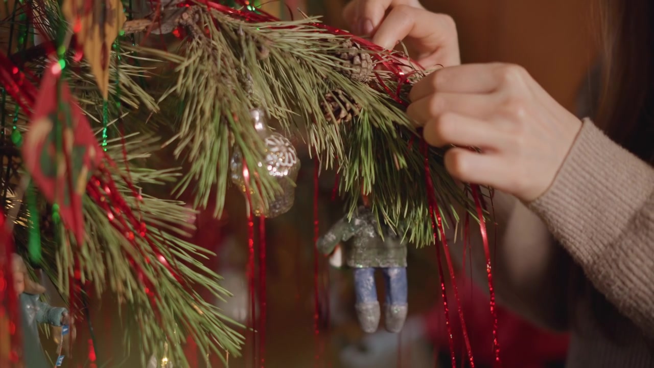 Arranjo festivo de ornamentos e decorações. Close-up de mãos arrumando decorações de feriado cintilantes. Imagem detalhada de dedos arrumando ornamentos brilhantes e festão durante os preparativos de feriado.
