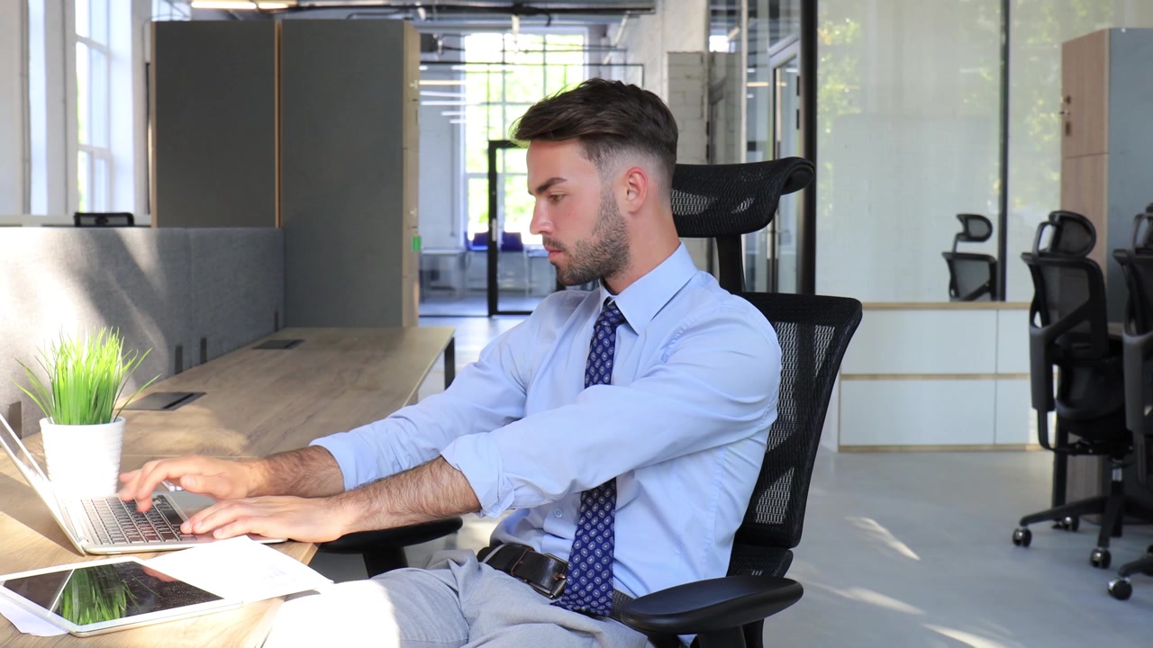 Giovane uomo d'affari che lavora con laptop e tablet in un ufficio moderno