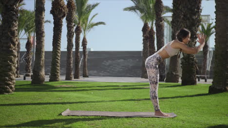 mujer haciendo una postura de palmera en el parque. chica practicando yoga al aire libre