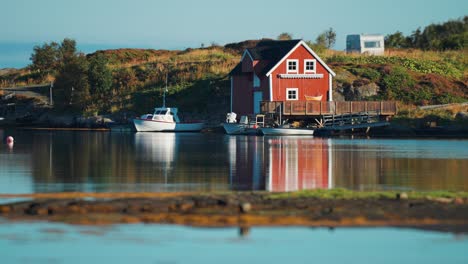 Scenic-view-of-a-red-house-on-a-wooden-pier,-with-small-boats-and-calm-waters-reflecting-the-scene