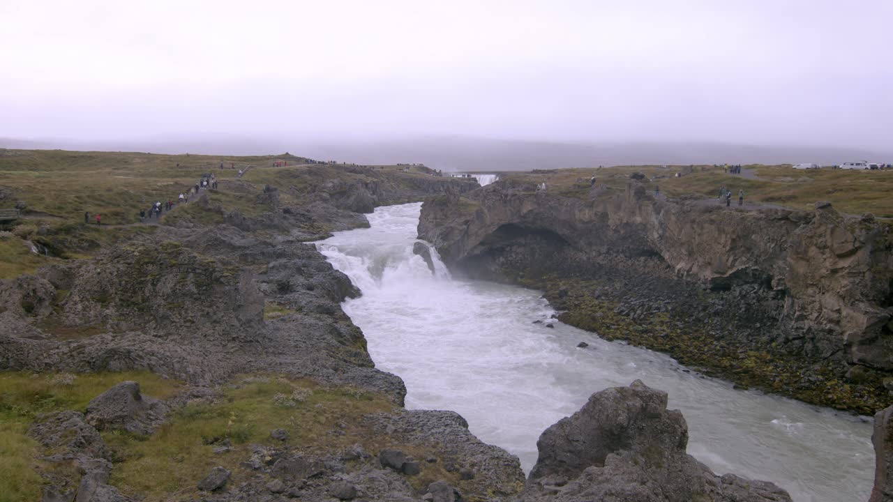 Majestic view of Goðafoss waterfall in Iceland with rugged cliffs and a cloudy sky in the background
