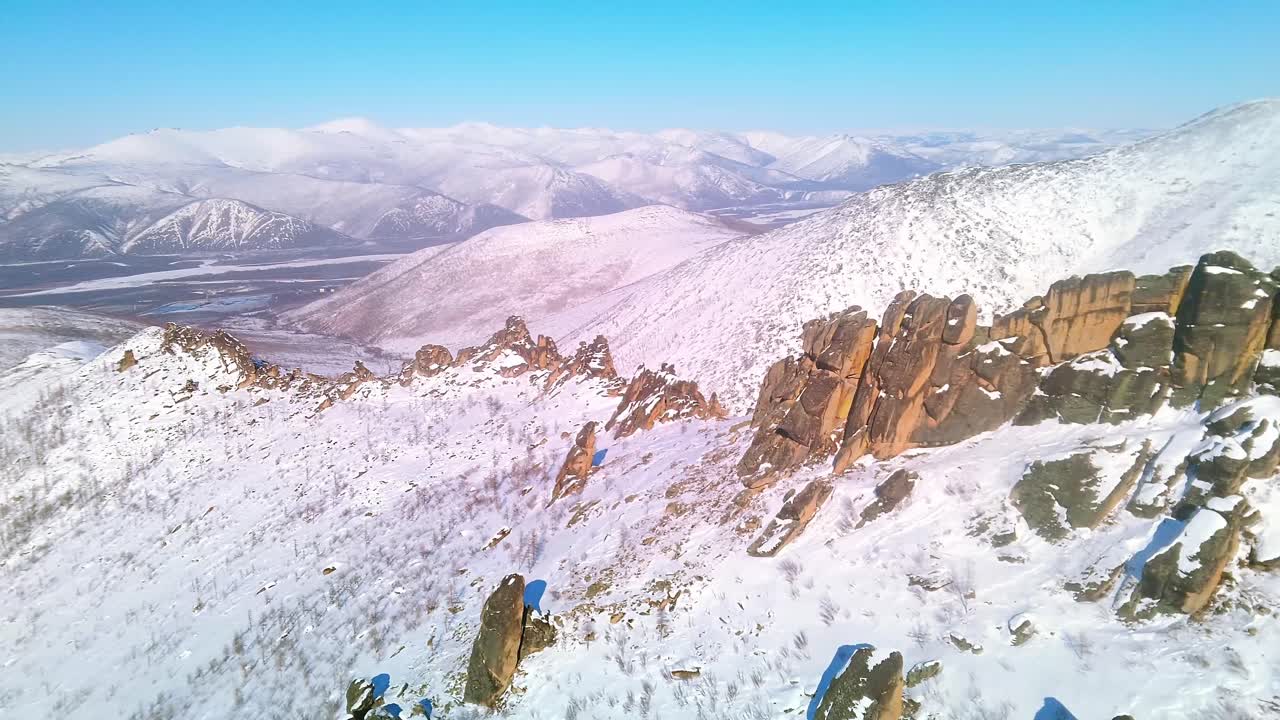 rocas en invierno disparadas desde un avión no tripulado en un clima soleado contra el telón de fondo de las montañas y el cielo azul