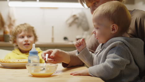 mother feeding toddler at kitchen table