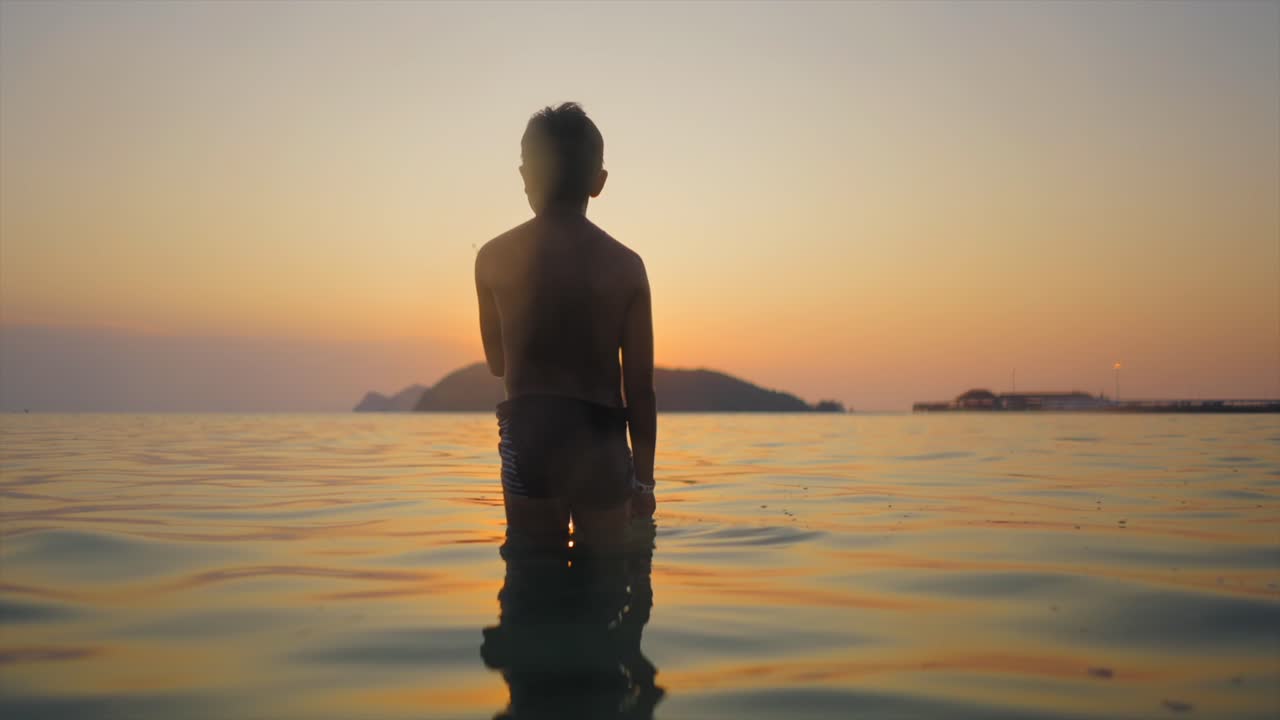 Child Standing in Ocean at Sunset