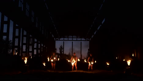 Professional-fire-show-in-the-old-hangar-of-the-aircraft-show-professional-circus-artists-three-women-in-leather-suits-and-a-man-with-two-flamethrowers..