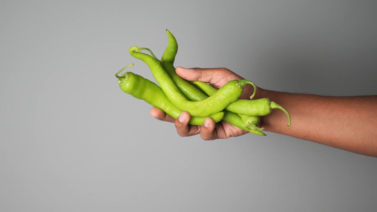 Hand holding green chili peppers