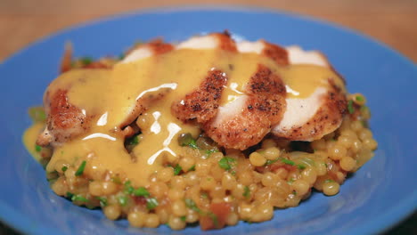 Close-up-view-of-a-serving-of-maple-Dijon-chicken-slices-covered-in-gravy-on-a-bed-of-couscous