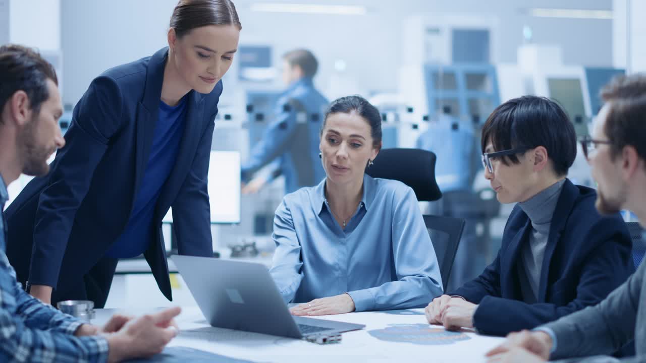 sala de reuniones moderna de la oficina de la fábrica: la gerente de proyecto confiada habla con un equipo diverso de ingenieros, empresarios e inversores sentados en la conferencia. optimización de las instalaciones de fabricación