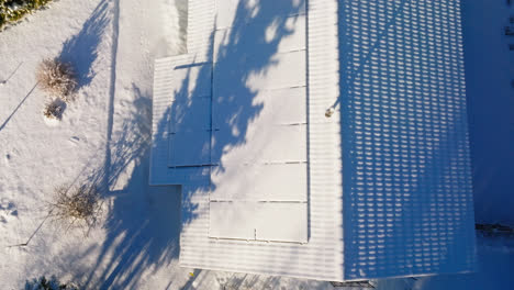 drone disparado desde arriba sobre paneles solares cubiertos de nieve, en el techo de una casa, hora dorada