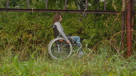 Woman with disability moves looking through shabby fence
