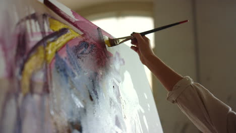 unknown woman painting in art studio. talented painter holding brush indoors.