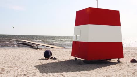 man sitting on beach filming ocean