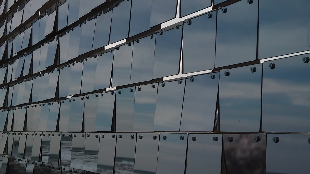 Rows of reflective plexiglass panels moving in tandem with the wind, slow motion medium shot