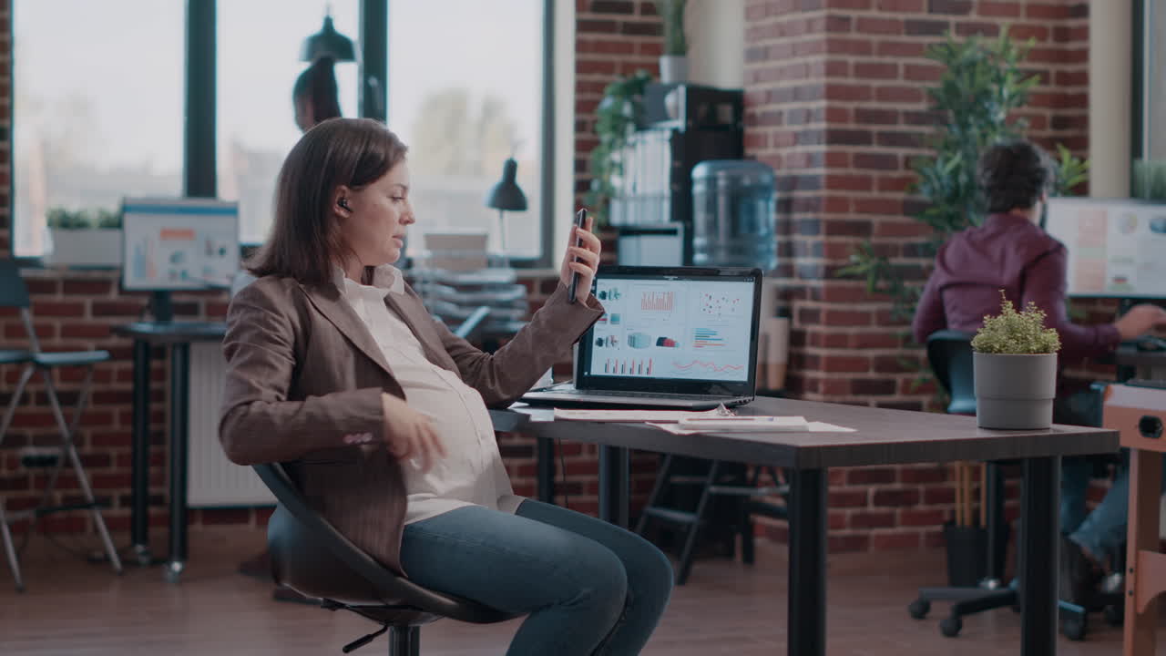 Woman expecting child holding smartphone to talk on video call