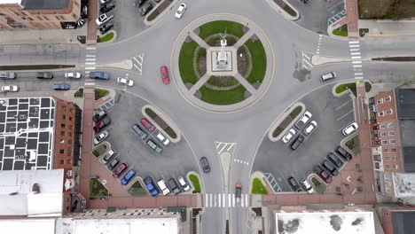 Angola,-Indiana-town-square-roundabout-with-cars-moving-around-and-drone-video-looking-down-and-moving-forward