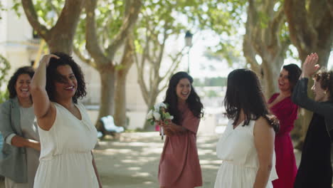 lesbian couple throwing bridal bouquet together in park