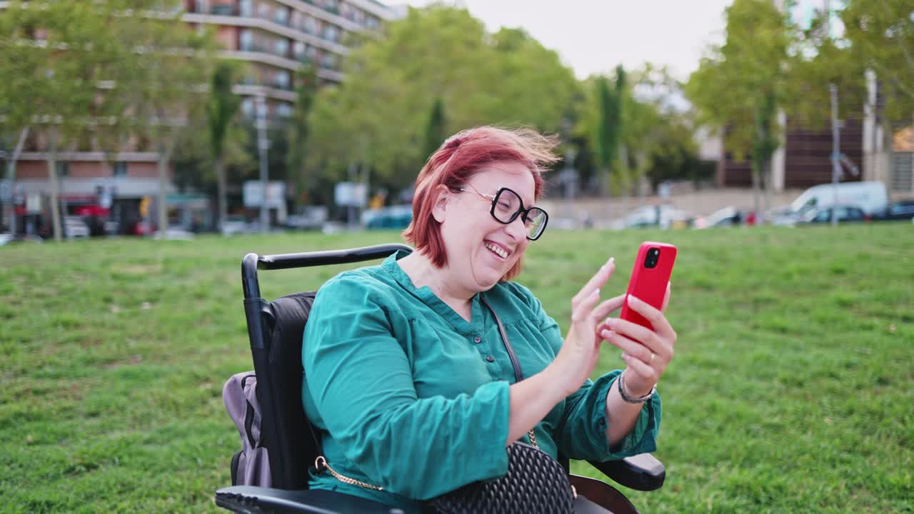 Donna felice in carrozzina elettrica che usa lo smartphone al parco