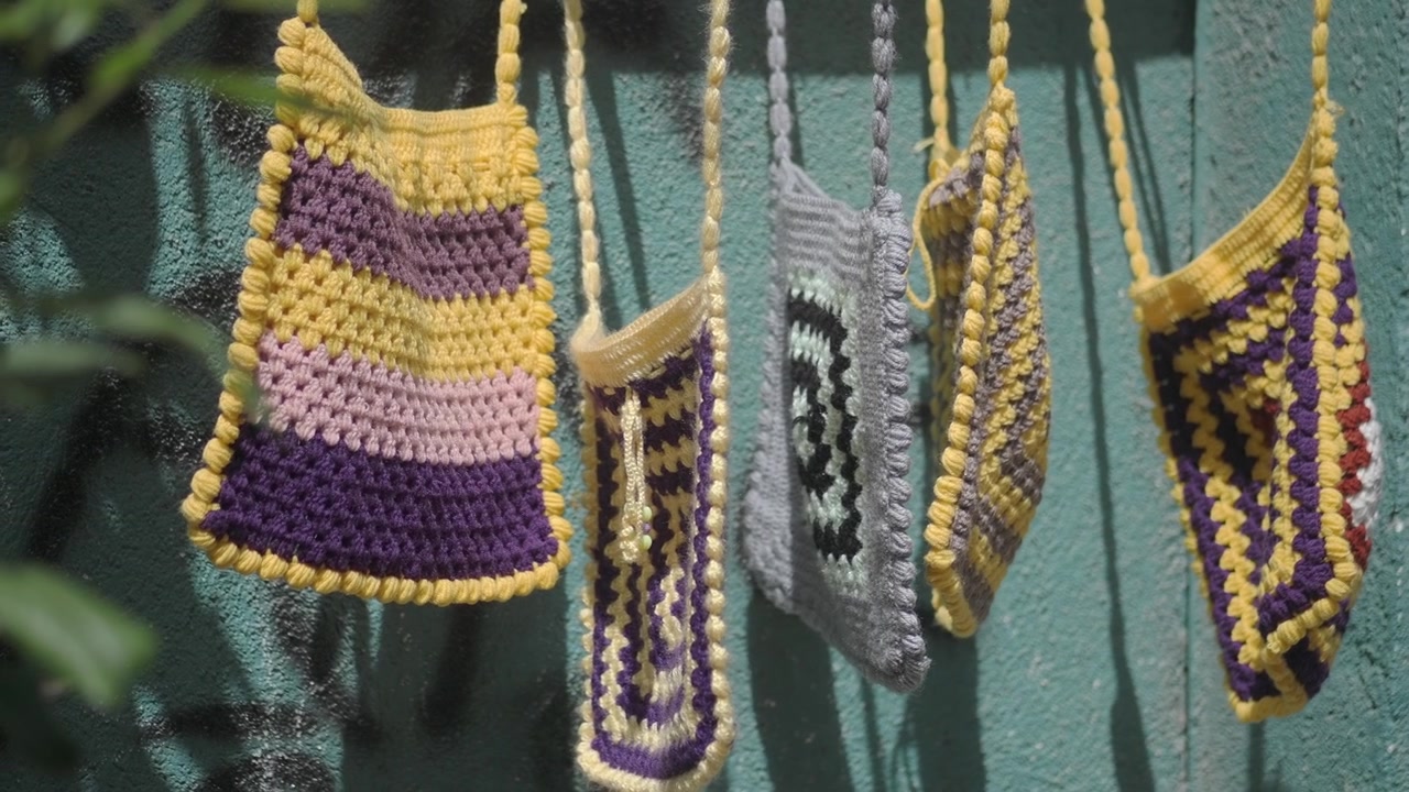 Bolsos de ganchillo artesanales y coloridos colgados al aire libre.