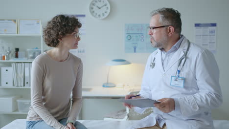 doctor and female patient sitting on examination table having talk in clinic