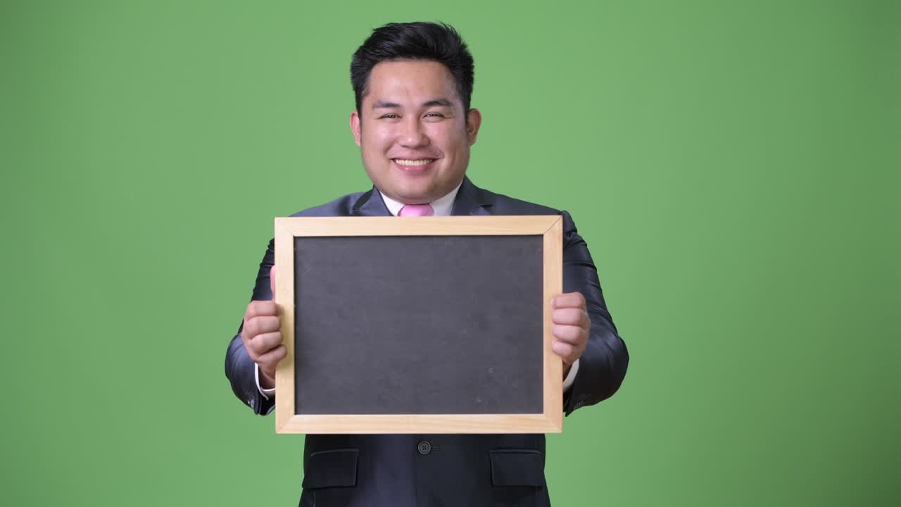 초록색 배경에 젊은 잘생긴 과체중 아시아 사업가