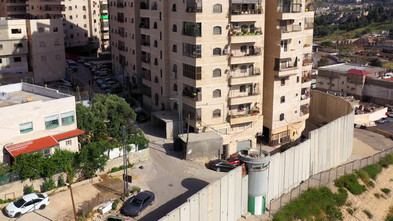 Aerial view of the Israeli separation wall in Jerusalem, with residential buildings and a watchtower