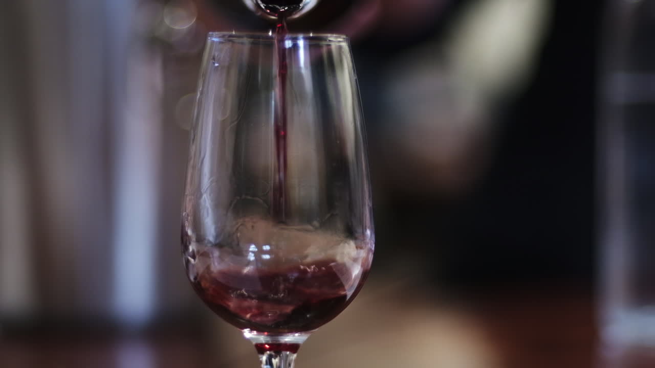Vino rosso versato nel bicchiere con sfondo di ristorante.