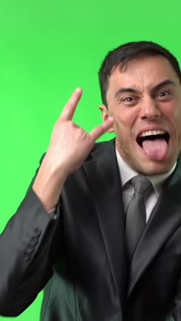 man in suit making funny faces and rock gestures on green screen