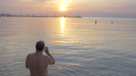 back view of man talking over phone while watching sunset