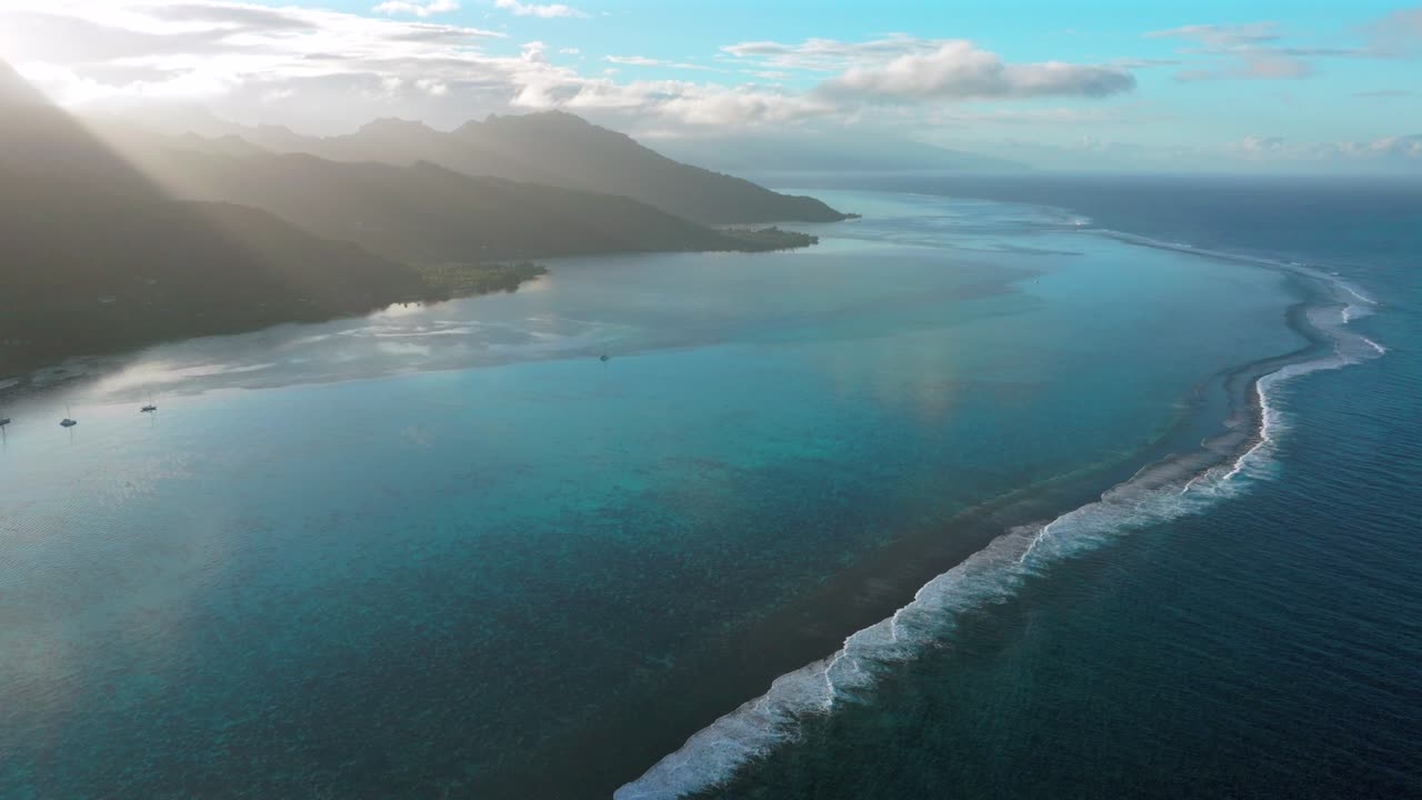 Morning sunrise boats Passe clear skies Moorea island Cooks Opunohu bay French Polynesia aerial drone lagoon coral reef waves Mount Mauaroa Tohivea Rotui Haapiti Pacific Ocean circle right motion