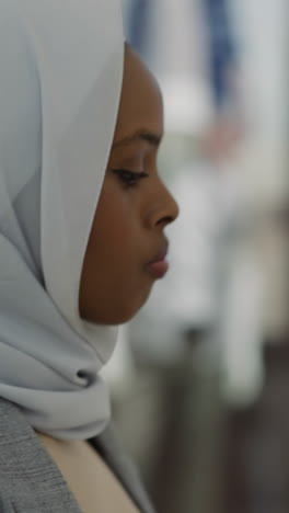 african-american woman with white hijab walks past blurry fashion boutique stores in shopping mall closeup slow motion. muslim lady during shopping