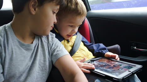 boys with tablet computer during traveling by car