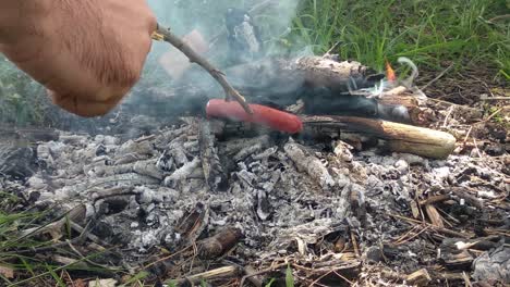 sausage roasting on fire while hiking the mountains at summer in a bright summer day