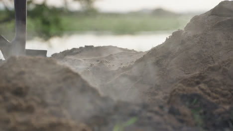 close up, slow motion, steaming is coming off the hot dirt being shovelled out of an underground cooking pit in the outback